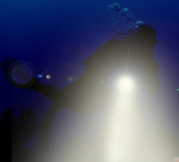 Night diver with flashlight on